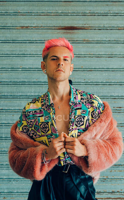 Junger homosexueller Mann in modischer Kleidung mit Maniküre und modernem Haarschnitt blickt in die Kamera auf blauem Hintergrund — Stockfoto