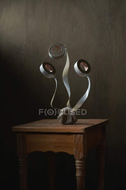 Pedra com rolos de fita adesiva representando conceito de buquê de flores em banquinho de madeira velho em fundo cinza — Fotografia de Stock