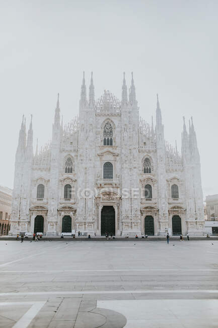 Старая каменная церковь снаружи с орнаментом между зданиями под блестящим небом в Милане Италия — стоковое фото