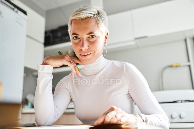 Crop adulto astrólogo feminino com maquiagem tocando rosto e queixo enquanto olha para a câmera em casa — Fotografia de Stock