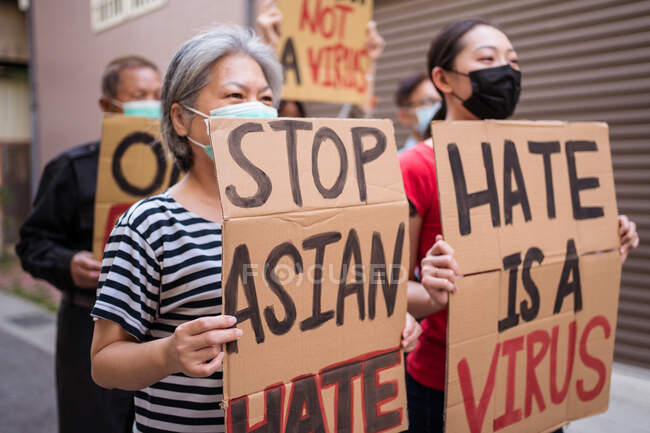 Ethnische Aktivisten mit Ich bin kein Virus und einer Rasse Inschriften auf Plakaten während Stop asiatischen Hassbewegung in der Stadt — Stockfoto