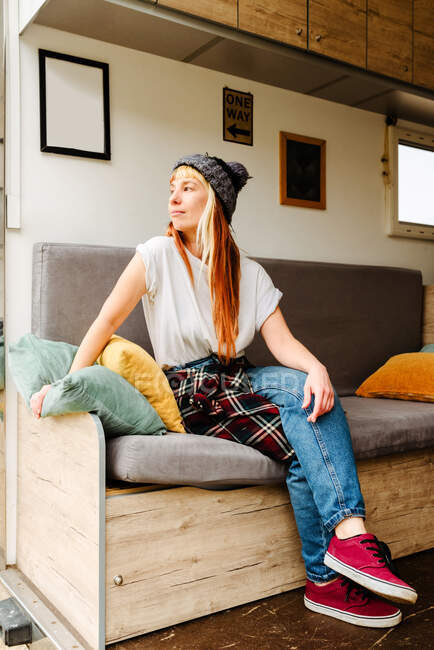 Thoughtful traveling female hipster sitting on couch in truck and enjoying vacation near lake — Stock Photo