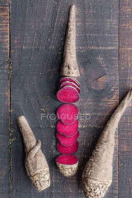 Zusammensetzung aus natürlicher biologischer Rote Bete in Scheiben geschnitten und auf schäbiger Holzoberfläche angeordnet — Stockfoto