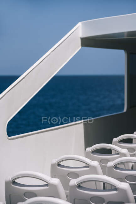 Empty white chairs on deck of cruise boat sailing in blue sea water — Stock Photo