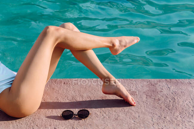 Cultures anonymes pieds nus femmes voyageurs touchant l'eau ondulée brillante dans la piscine pendant le voyage — Photo de stock