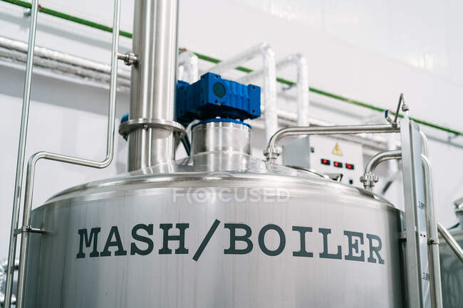 Stainless steel reservoir with title and different tubes with shiny surface in light brewery — Stock Photo