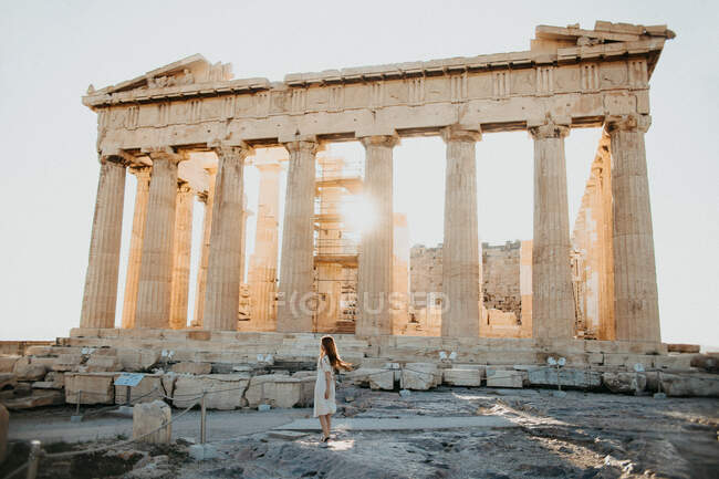 Side view of anonymous female tourist against partially destroyed aged temple of Athenian Empire in Greece on sunny day — Stock Photo