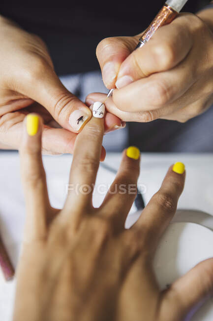 From above of crop unrecognizable manicurist doing nail art fpr female client in beauty salon in daylight — Foto stock