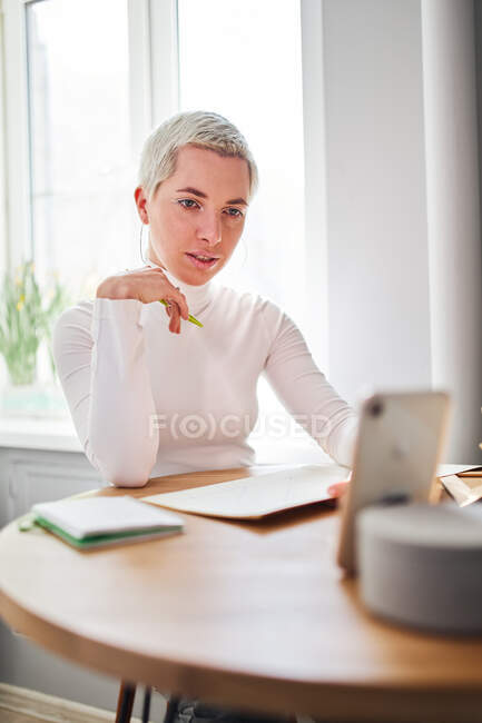 Female blogger talking about astrology while recording video on cellphone at desk in sunlight — Stock Photo