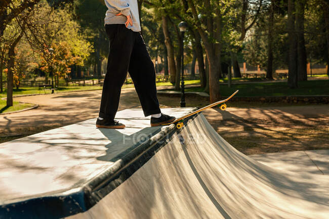 Jovem patinador em sua prancha se preparando para saltar na rampa no parque de skate urbano — Fotografia de Stock