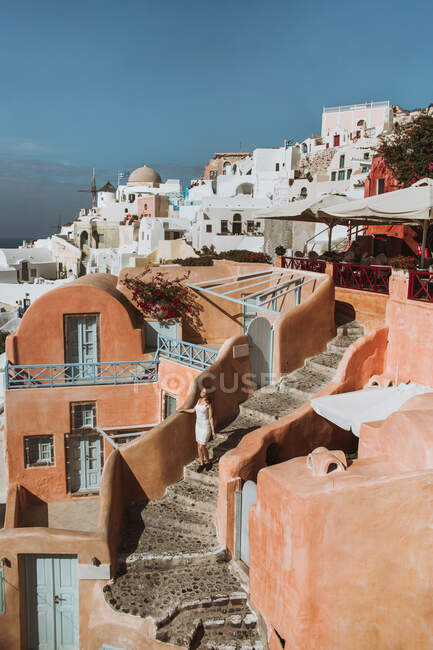 Mulher irreconhecível em sundress branco em pé em escadas de pedra resistido na histórica aldeia velha no dia ensolarado na Grécia — Fotografia de Stock