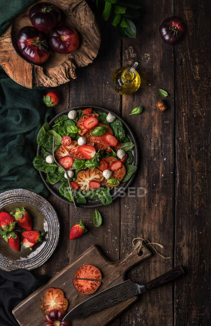Здоровий салат з помідорами та полуницею на дерев'яному сільському столі — стокове фото