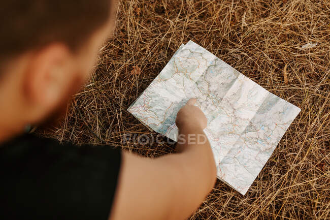 Dall'alto ritagliato viaggiatore maschio irriconoscibile puntando mentre guardando in una mappa sulla foresta — Foto stock