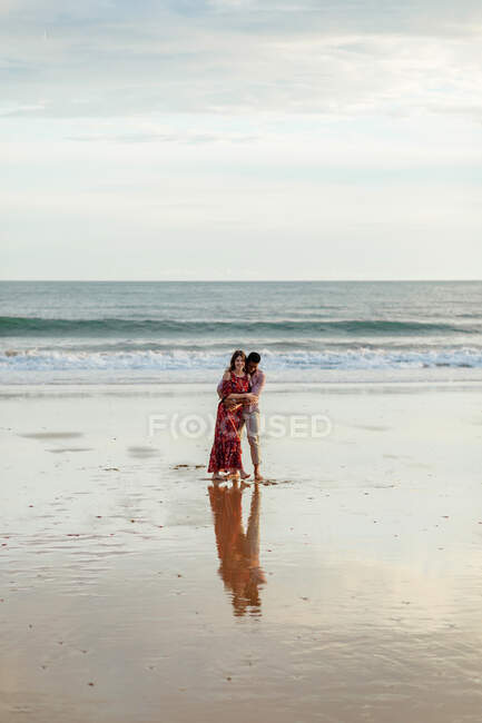 Aimer l'homme embrasser la femme par derrière tout en passant la journée d'été ensemble sur le bord de la mer — Photo de stock