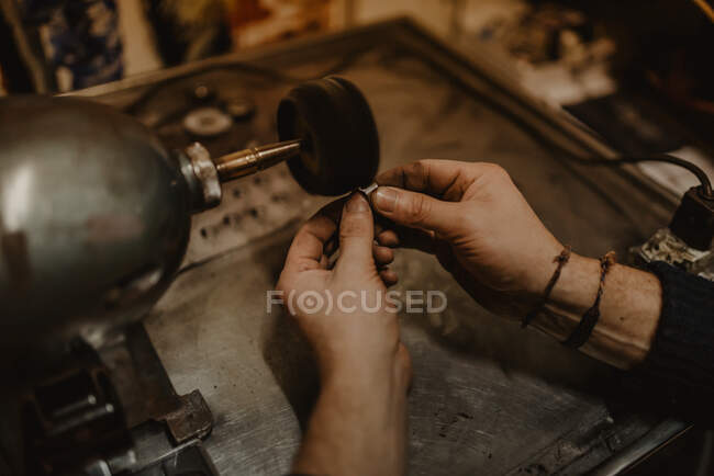 Mains d'orfèvre masculin anonyme utilisant un outil manuel pour façonner une bague en métal en atelier — Photo de stock