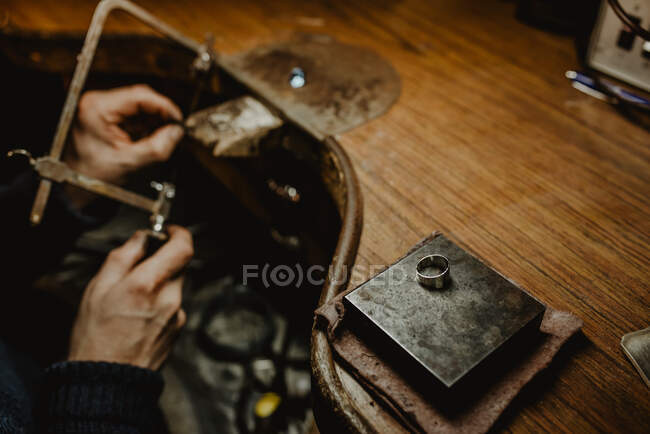 Голдсміт вирізає метал пилкою під час виготовлення ювелірних виробів у майстерні. — стокове фото