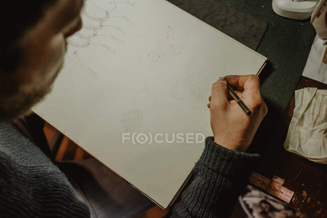 Korngoldschmied zeichnet Ringskizze im offenen Notizblock während der Arbeit in der Werkstatt — Stockfoto