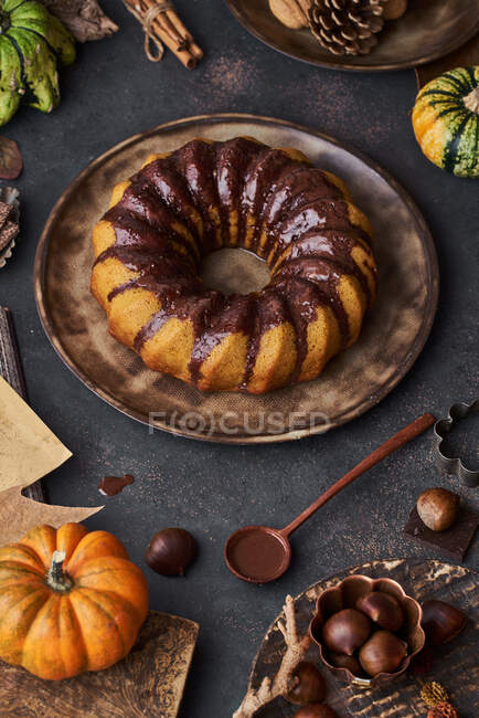 Dall'alto torta di zucca appetitosa saporita con crema di cioccolato su tavolo decorata con verdure di autunno — Foto stock