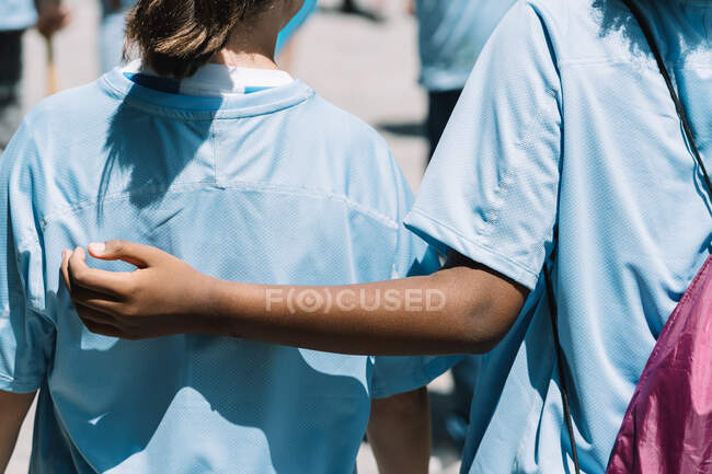 Back view of crop unrecognizable multiracial teen friends in blue uniform participating in environmental volunteer campaign in summer day — Stock Photo