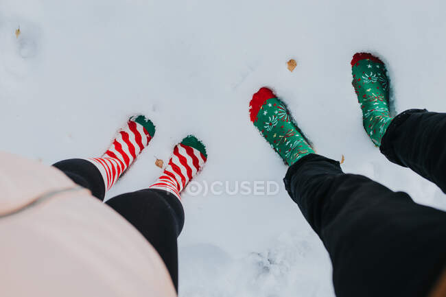 De los pies arriba en los calcetines del hombre y la mujer de pie en el suelo de nieve - foto de stock