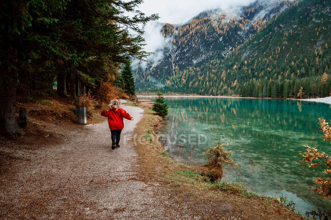 Mulher vestida de vermelho correndo perto do lago — Fotografia de Stock