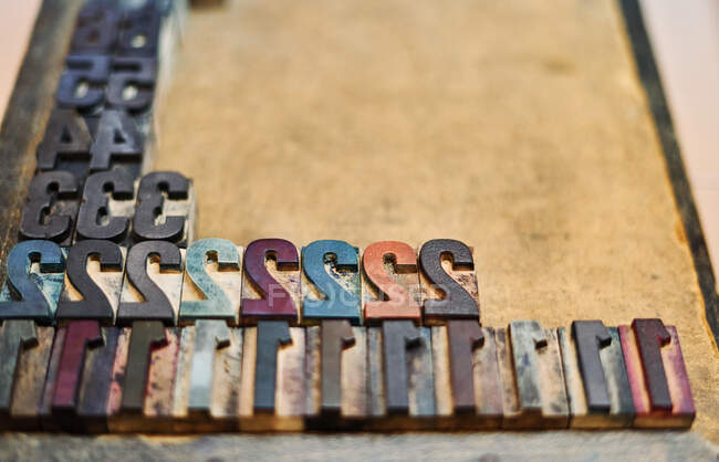 High angle of collection of grungy metal letterpress numbers placed on tray in workshop — Stock Photo