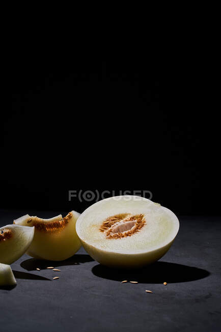 Vista lateral de un melón fresco cortado por la mitad sobre fondo negro - foto de stock
