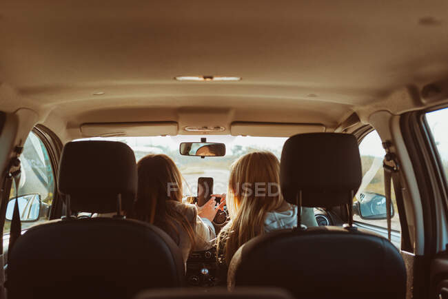 Back view woman in car browsing phone — Stock Photo