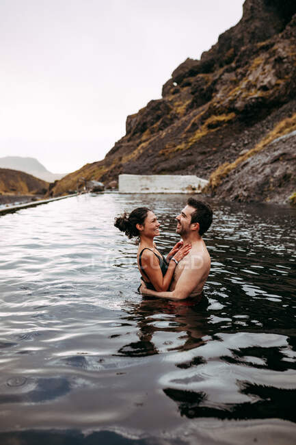 Paar lacht im Wasser zwischen Bergen — Stockfoto