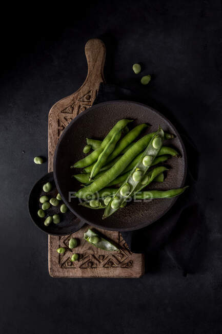 Vista superior de la composición de dos cuencos con frijoles franceses crudos orgánicos y legumbres en la tabla de cortar decorativa - foto de stock