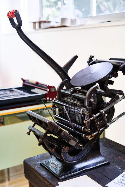 Ретро-потёртый штамповочный станок с металлическими деталями, размещенными на деревянном верстаке в типографии — стоковое фото