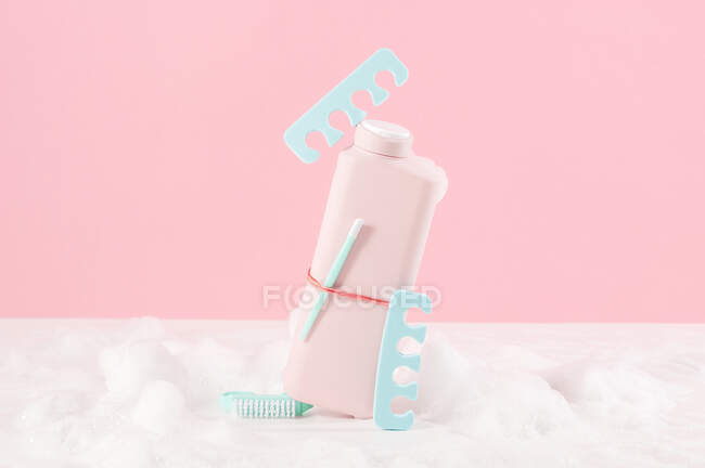 Stillleben einer Flasche Badegel zwischen Schaum auf rosa Hintergrund — Stockfoto