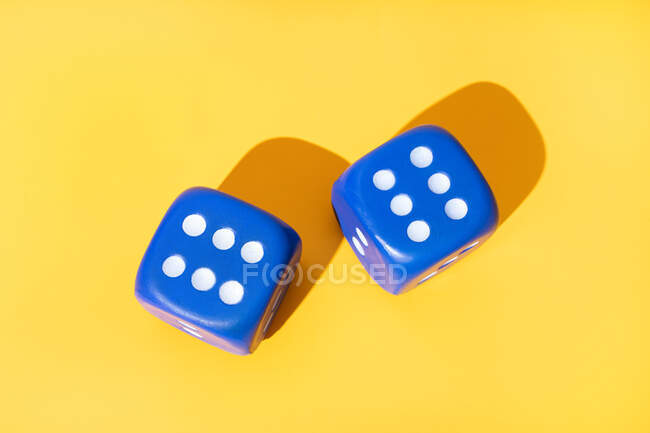 Top view of blue dice with even number of white pips on yellow background with shadows — Stock Photo