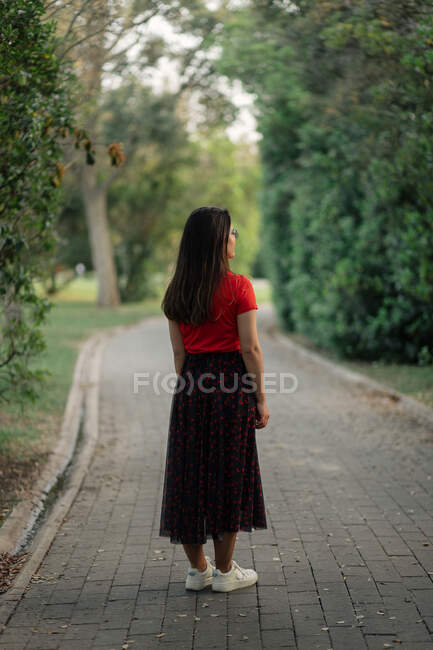 Модная женщина в летней одежде стоит на лужайке в саду и смотрит в камеру — стоковое фото