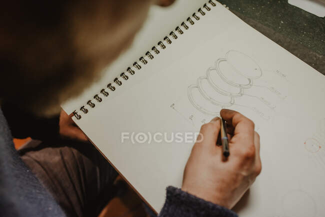 Korngoldschmied zeichnet Ringskizze im offenen Notizblock während der Arbeit in der Werkstatt — Stockfoto
