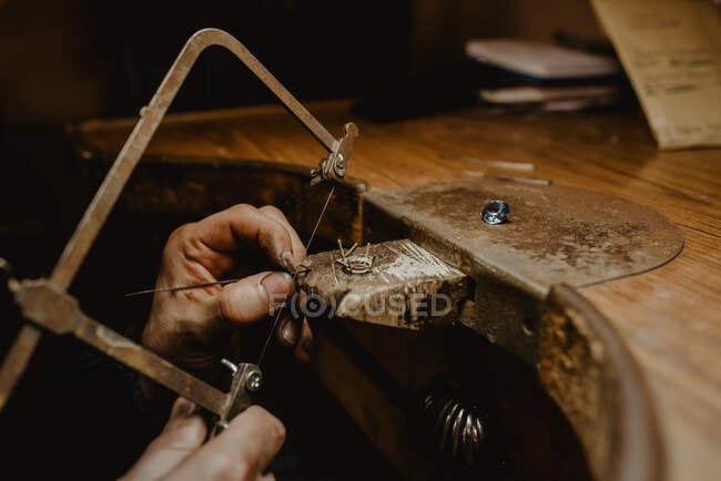 Anonymer Goldschmied schneidet Metall mit Säge, während er Schmuck in der Werkstatt herstellt — Stockfoto