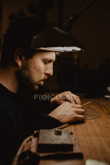 Jeweler holding unfinished ring in dirty hands and checking quality in workshop — Stock Photo