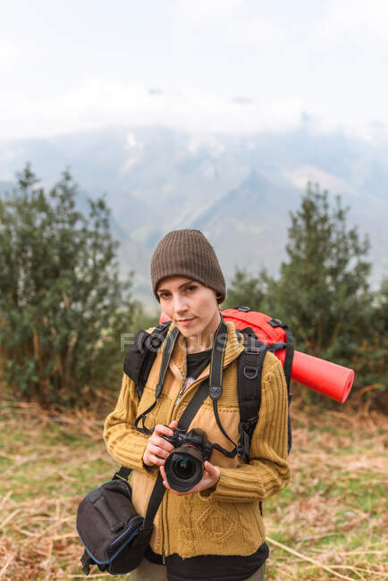 Mochilera femenina tomando fotos del paisaje montañoso durante el viaje - foto de stock