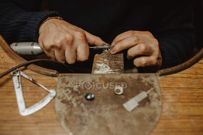 Нерозпізнаний ювелір за допомогою професійної полірувальної машини на робочому місці при виготовленні металевого кільця в майстерні. — стокове фото