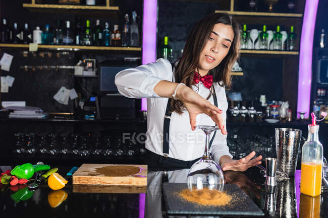 Jovem garçonete em roupa elegante preparando coquetel com açúcar enquanto está no balcão no bar moderno — Fotografia de Stock