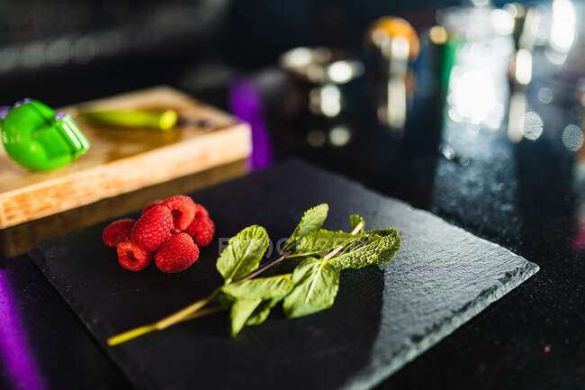 Peppermint and raspberry on a slate board on a bar table for cocktail preparations — Stock Photo