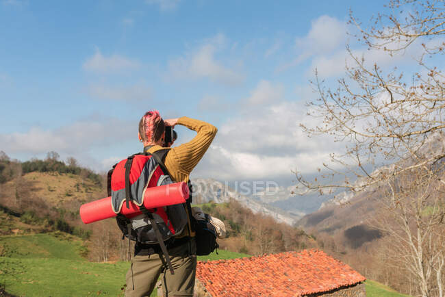 Вид ззаду анонімного жіночого рюкзака, який фотографує гірський пейзаж під час подорожей — стокове фото