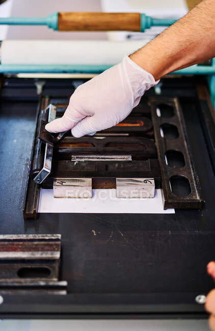 Crop unrecognizable craftsman making imprint of metal letters on paper while working in printing workshop — Stock Photo