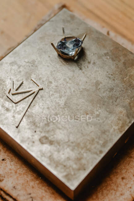 Glänzender Metallring mit wunderschönem blauen Edelstein auf Holzoberfläche in Werkstatt platziert — Stockfoto