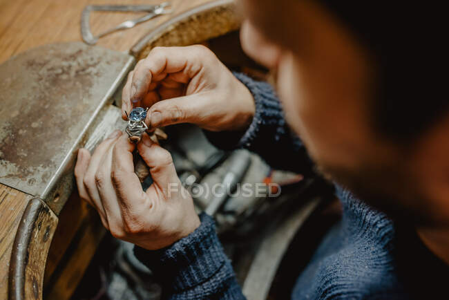 Anonymer Juwelier hält unfertigen Ring in schmutzigen Händen und überprüft Qualität in Werkstatt — Stockfoto