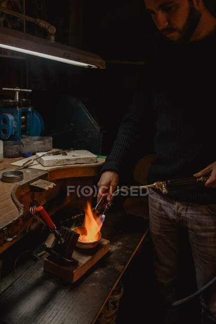 Ґолдсміт плавить метал для ювелірних виробів, стоячи біля майстерні. — стокове фото