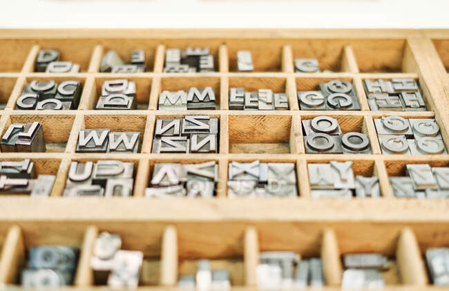 Набор металлических потрёпанных букв в деревянном ящике в типографии — стоковое фото