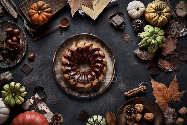 Dall'alto torta di zucca appetitosa saporita con crema di cioccolato su tavolo decorata con verdure di autunno — Foto stock