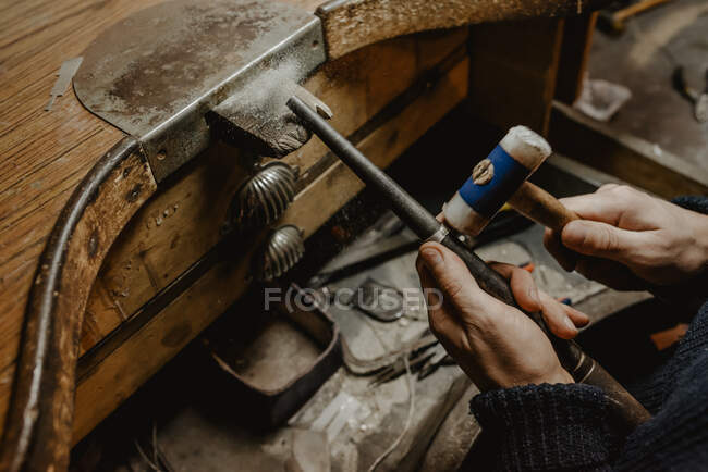 Анонімний золотошукач забиває і розширює кільце заготовки на металевій паличці під час роботи в майстерні — стокове фото