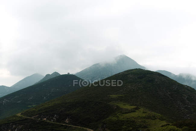 Dicke graue Wolken schweben am Himmel über grünen Hügeln an einem trüben Tag auf dem Land — Stockfoto